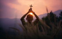 a boy holding up a cross praying 