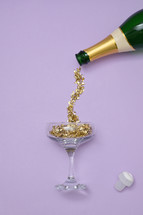 Champagne bottle with gold confetti pouring into glass