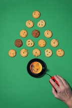 Coffee and cookies in the shape of a Christmas tree with computer mouse and hand on a green background
