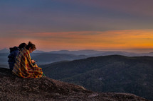women sitting on a mountaintop at sunrise 