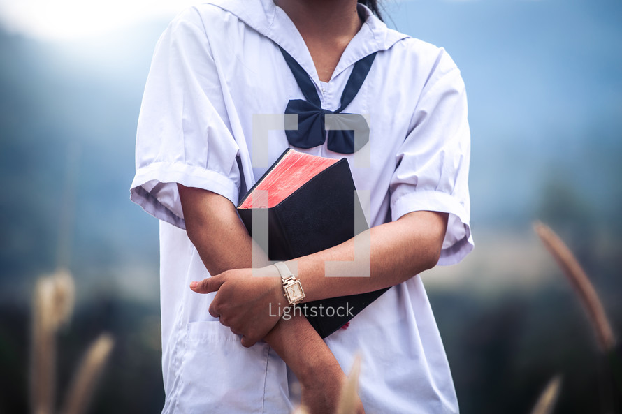 Girl holding bible at outdoors. Christian concept.