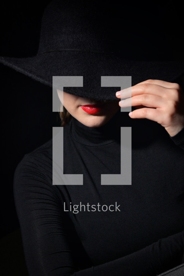 A Woman With Red Lips In A Black Hat On A Black Background