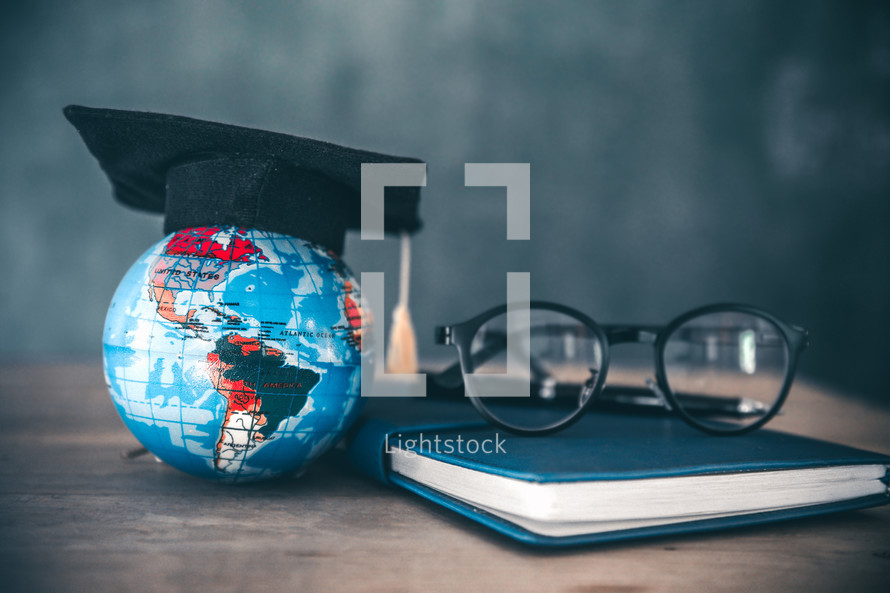 globe with graduation cap on a desk in a classroom 