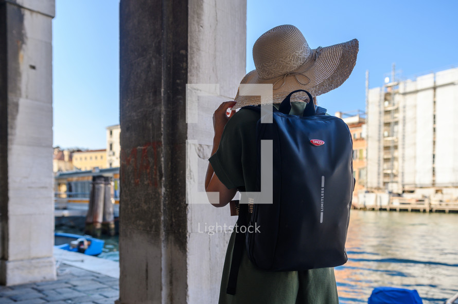 a woman in a sunhat looking out at a chanel in Venice 
