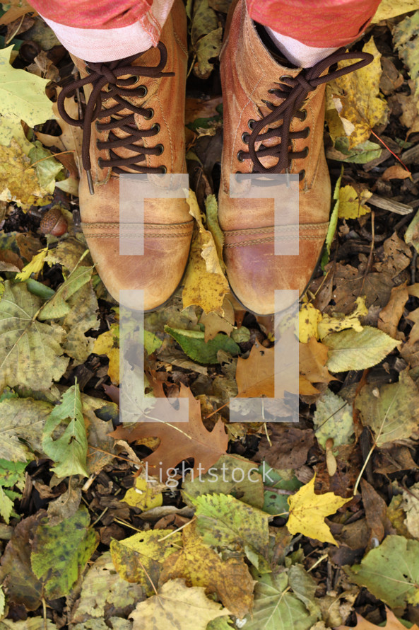woman's boots standing in fall leaves 