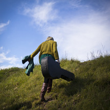 woman walking up a hill carrying a guitar case 