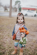 A girl carrying a doll and purse