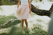 a young woman in a dress walking through a backyard 