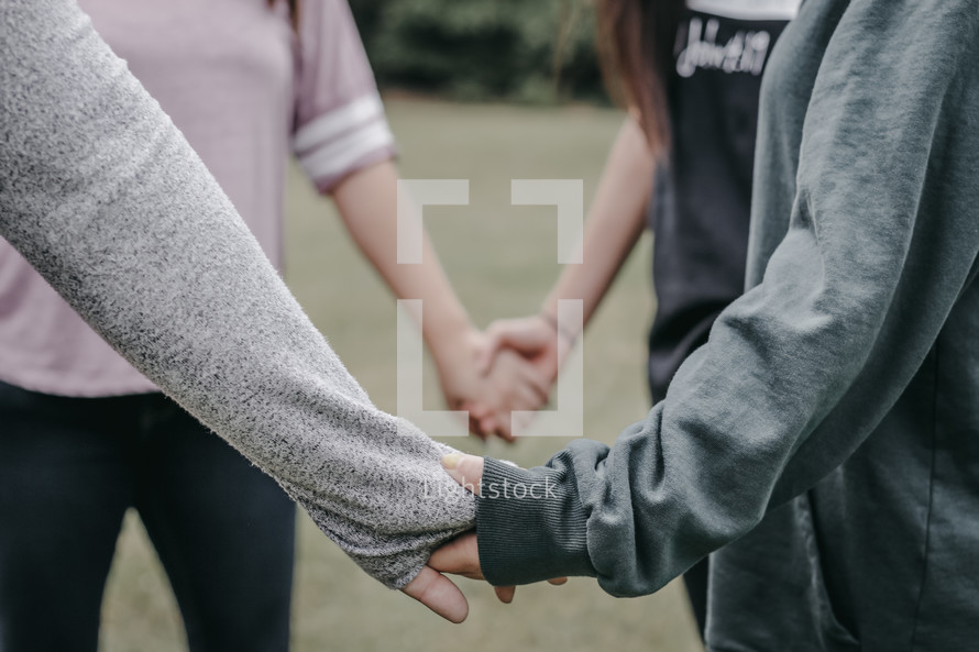 young women holding hands in prayer 