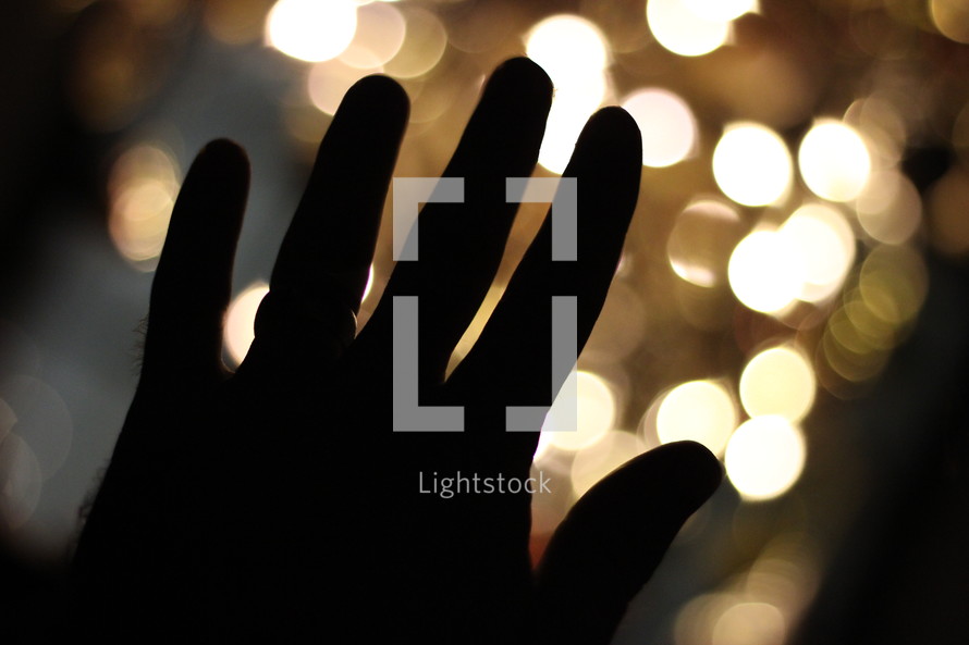 Silhouette of a hand in front of lights.