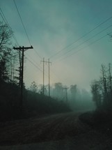 power lines and fog over a country road 