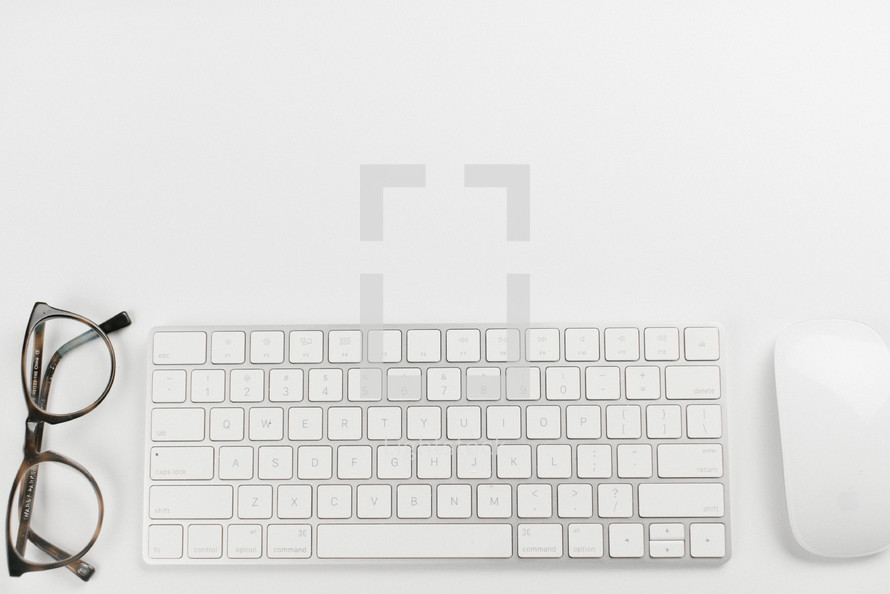 reading glasses, computer keyboard, and mouse on white background 