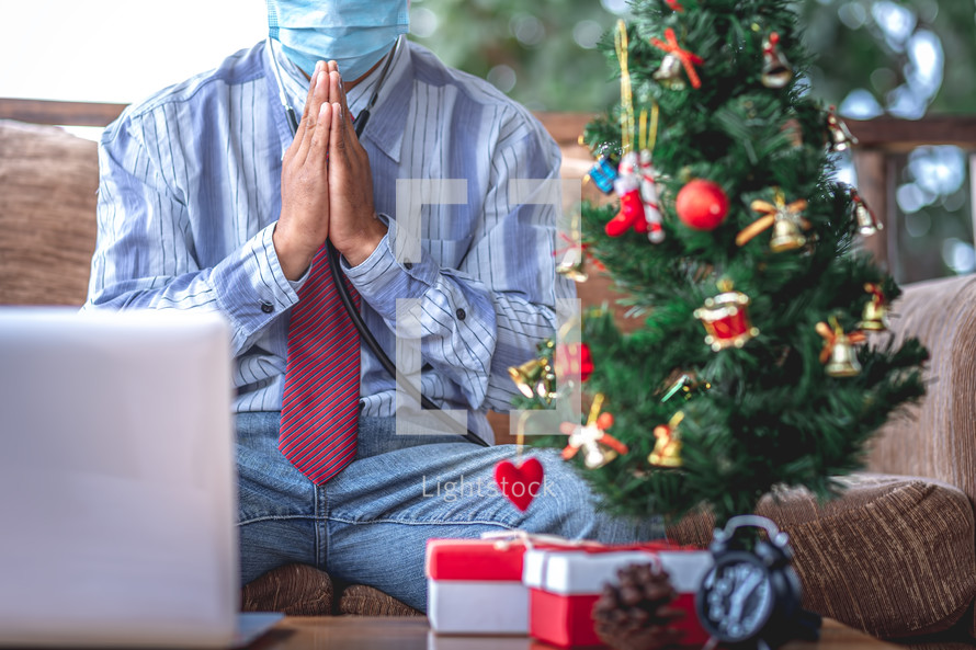 man praying looking at a computer screen for a online Christmas worship service 
