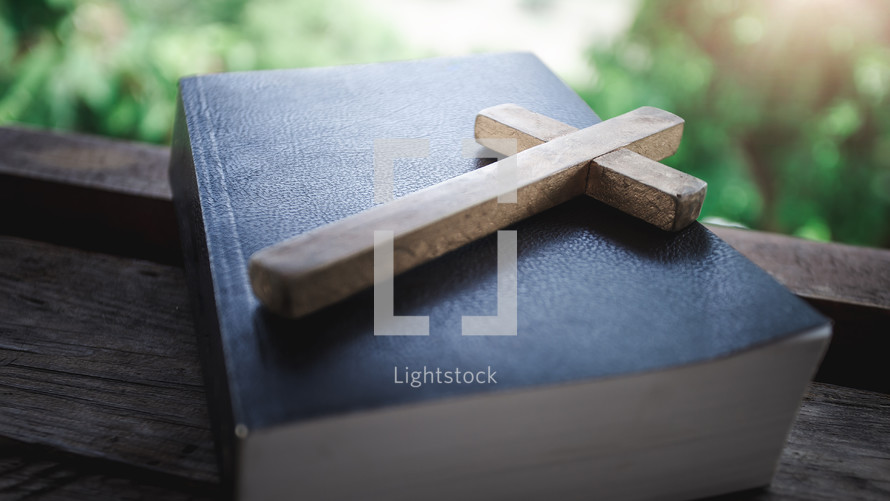 wooden cross on a Bible in a window 