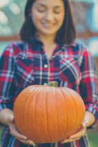 woman holding an orange pumpkin 