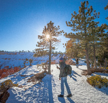 people hiking through the snow to get views of a red rock canyon 
