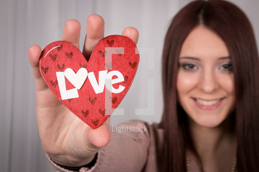 girl holding up a heart with the word love 
