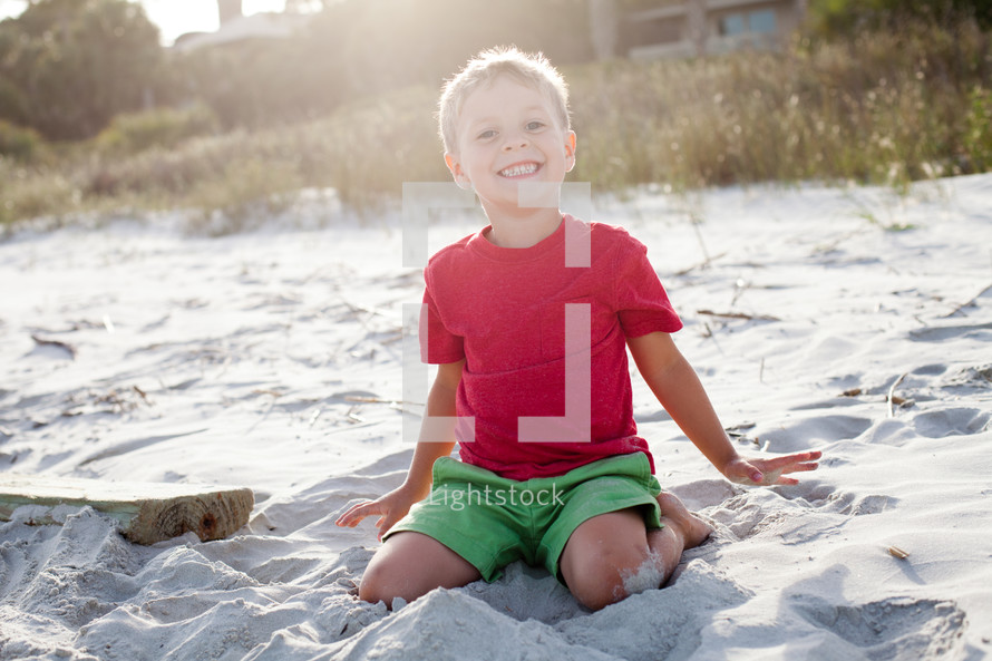 boy child sitting in the sand on a beach 
