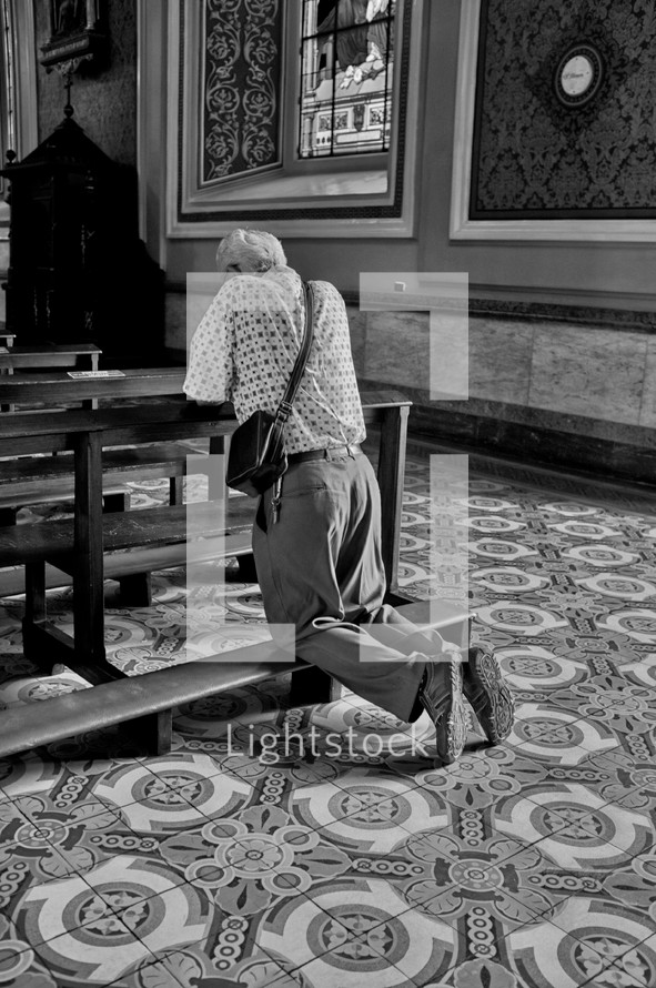 elderly man alone in a church praying 