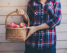 a woman holding a basket of apples 