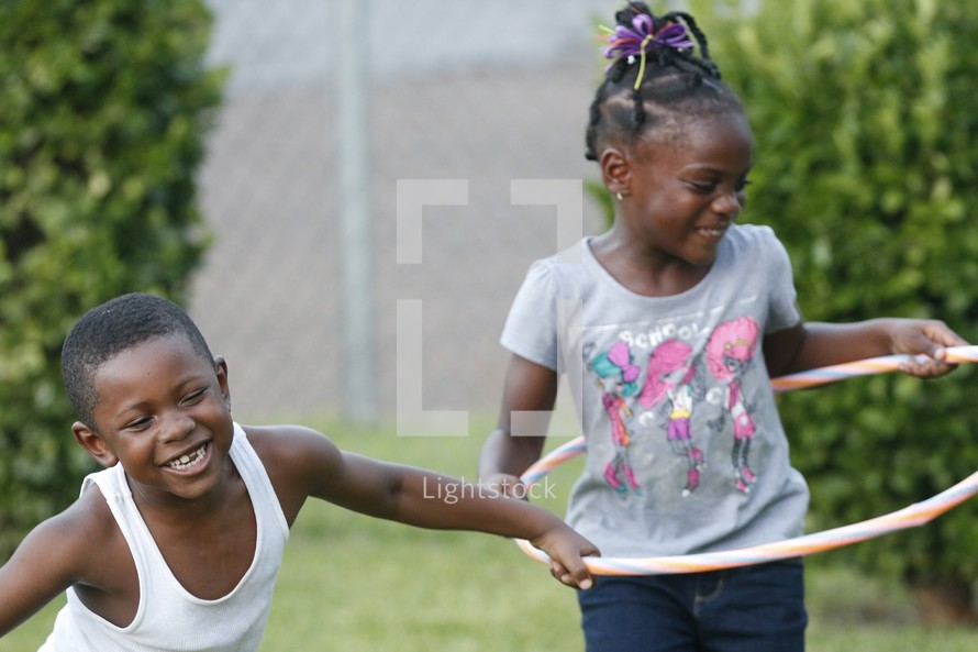 children playing outdoors with a hula hoop 