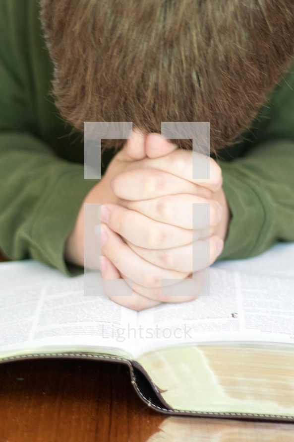a man praying over the pages of a Bible 