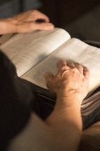 a man reading a Bible with hands on open Bible