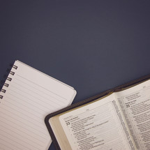 open Bible and notebook on blue background 