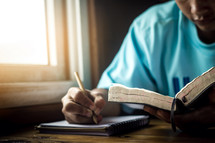 a man reading a Bible and taking notes 