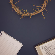 crown of thorns, notebook, and open Bible on blue 