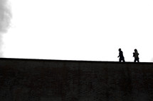 silhouettes walking across the top of a wall 