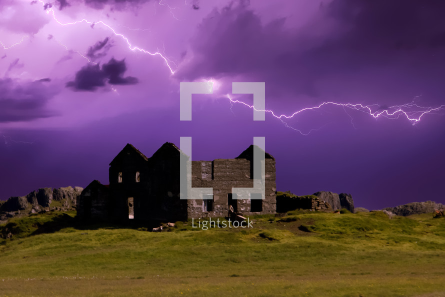 lightning in a purple sky over and abandoned house in ruins 
