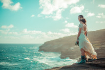 a bride and groom standing on a rocky shore 
