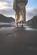 Jesus walking on a beach leaving footprints in the sand 