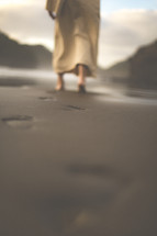 Jesus walking on a beach leaving footprints in the sand 