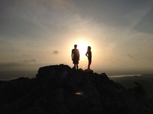 silhouette of a man and woman standing on top of a mountain 
