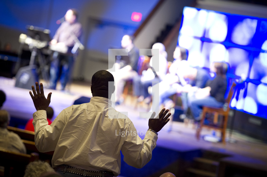 man with his hands raised in worship to God during a worship service 