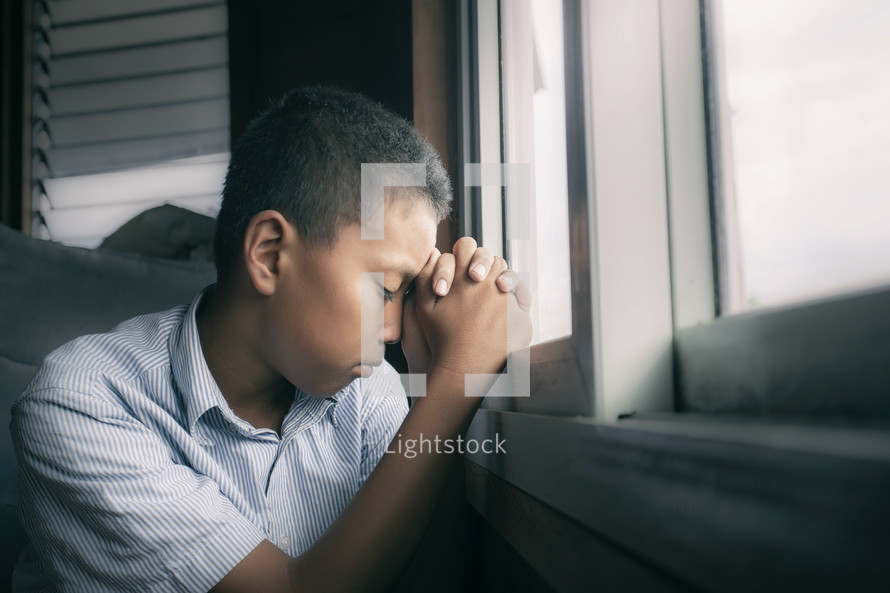 a boy praying in a window 