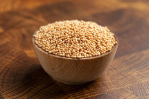 mustard seeds in a wooden bowl on a wood background 