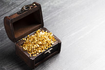 pieces of Gold in a Treasure Chest on a Wooden Table