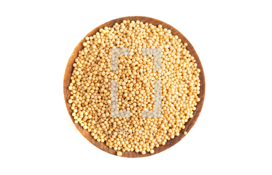 mustard seeds in a wooden bowl on a white background 