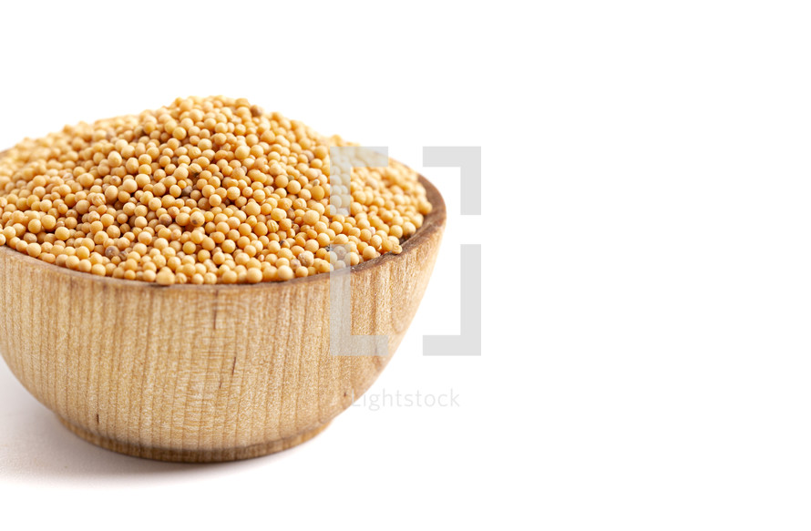 mustard seeds in a wooden bowl on a white background 