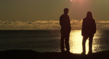 Silhouette of a couple standing on the beach by the ocean at night.