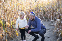 Man and daughter in corn stalks in the fall