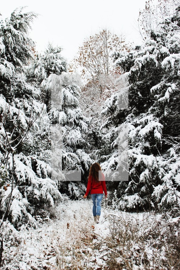 a woman walking in a winter forest 