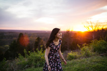 An Asian girl walking in a meadow at sunset 