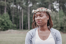 a woman with flowers in her hair standing outdoors 