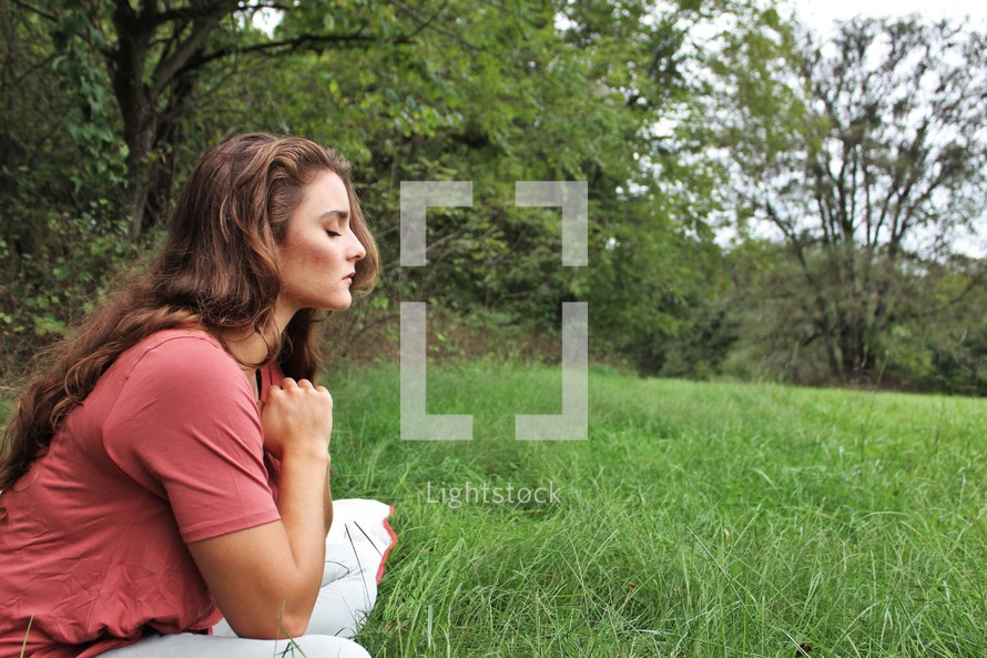 a woman praying outdoors alone 