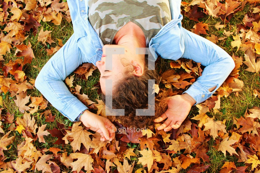 girl lying in fall leaves 