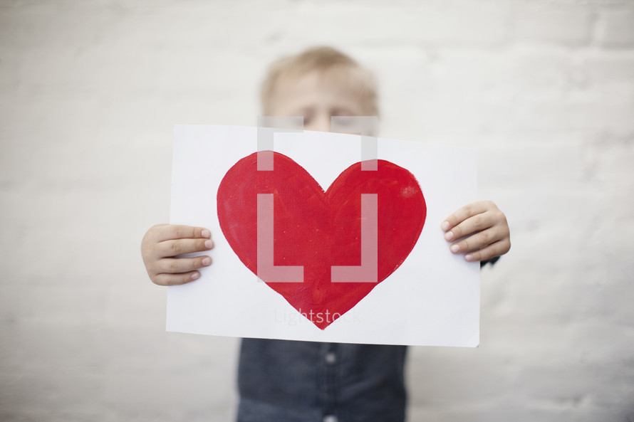 toddler boy holding a painting of a heart 